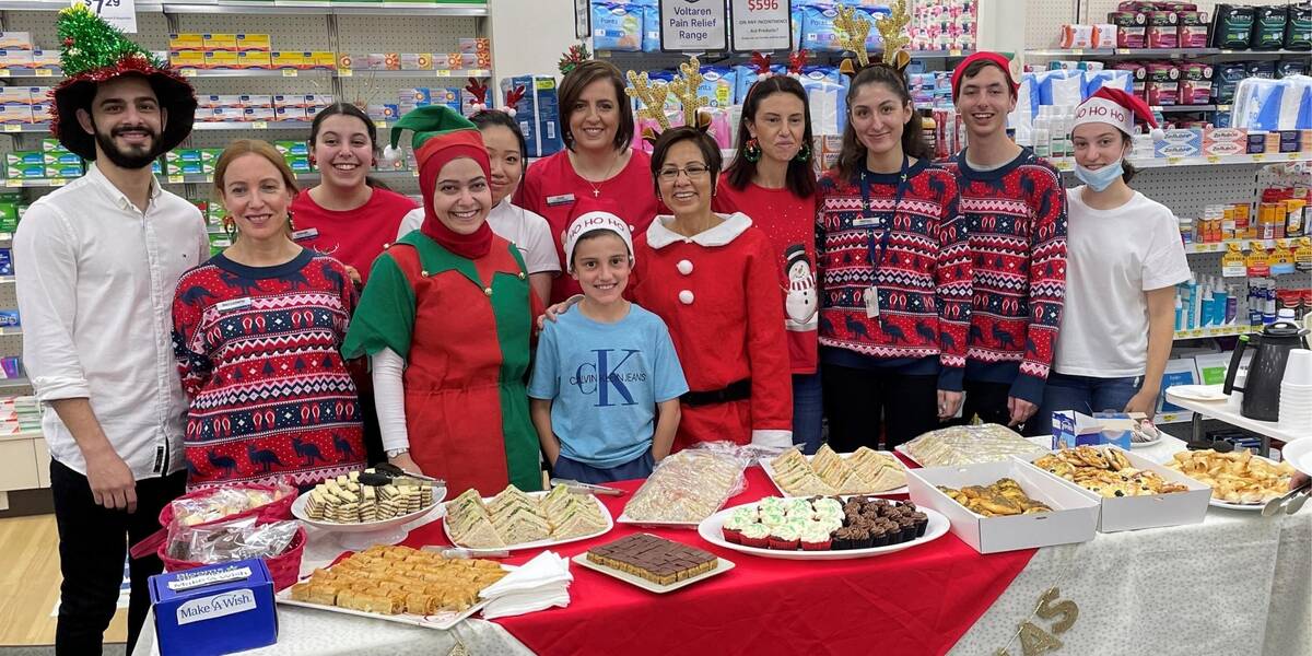 A group of staff from Blooms the chemist, in store, dressed up in red and green Christmas sweaters with a collection tin for Make-A-Wish
