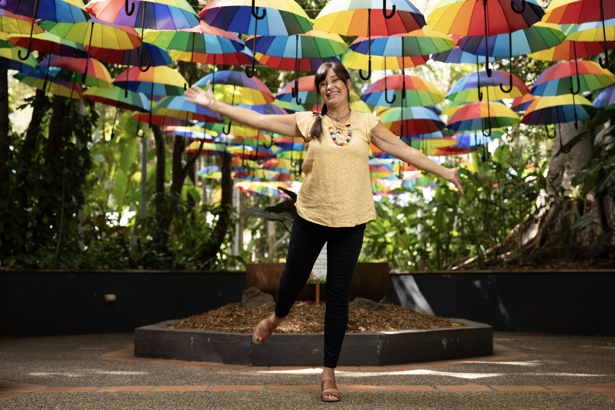 Happy artist stands in front of rainbow umbrellas