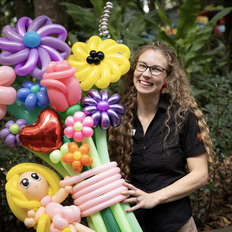 Smiling woman holds colourful inflatable flowers