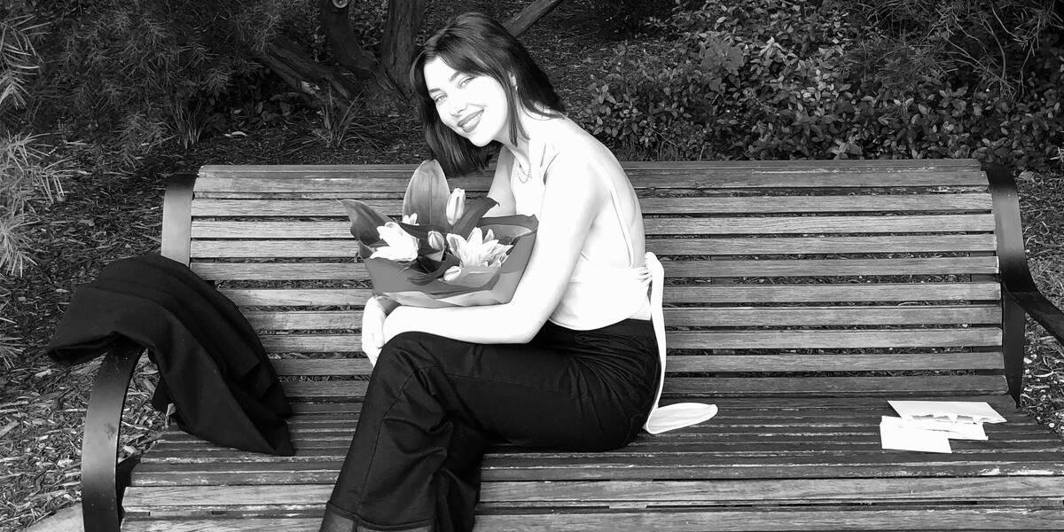 Make-A-Wish Australia wish kid Tara on a bench with flowers