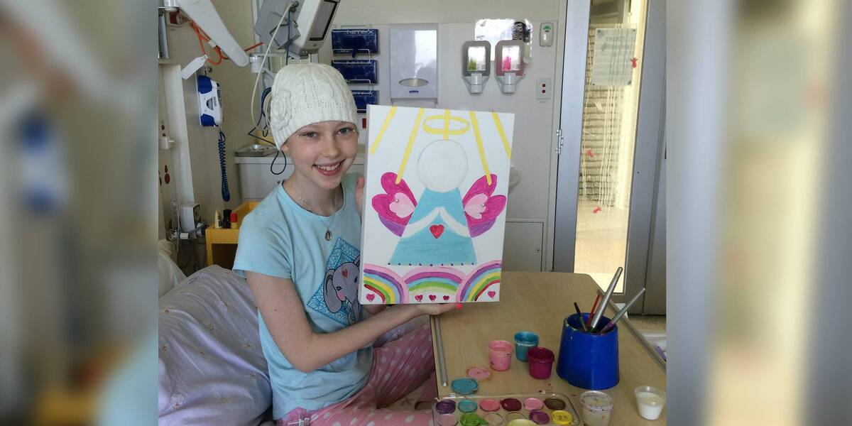 Make-A-Wish Australia wish kid Tara in hospital holding up a painting