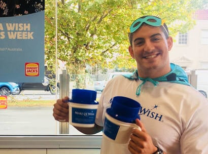 Make-A-Wish Australia event volunteer at a World Wish Day fundraiser holding collection tins