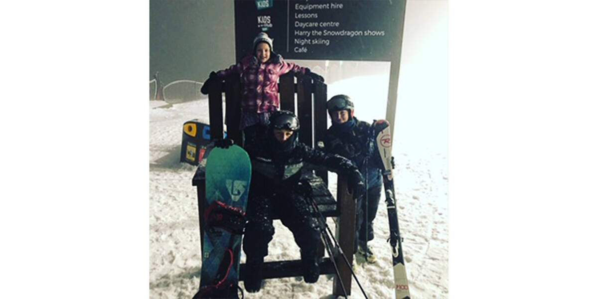 Harry and his brother stand next to a snowman that is almost as tall as them.