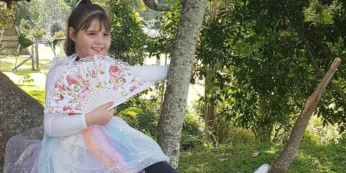 Make-A-Wish Australia wish child Cara sat on a tree branch at her garden party wish