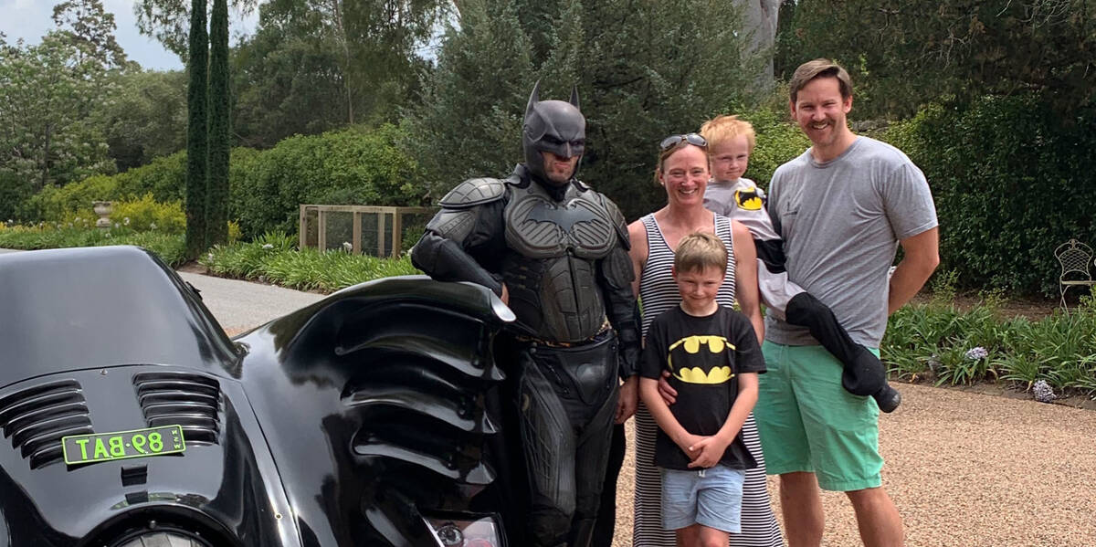 Make-A-Wish kid Rory stands with his family and batman, next to the batmobile